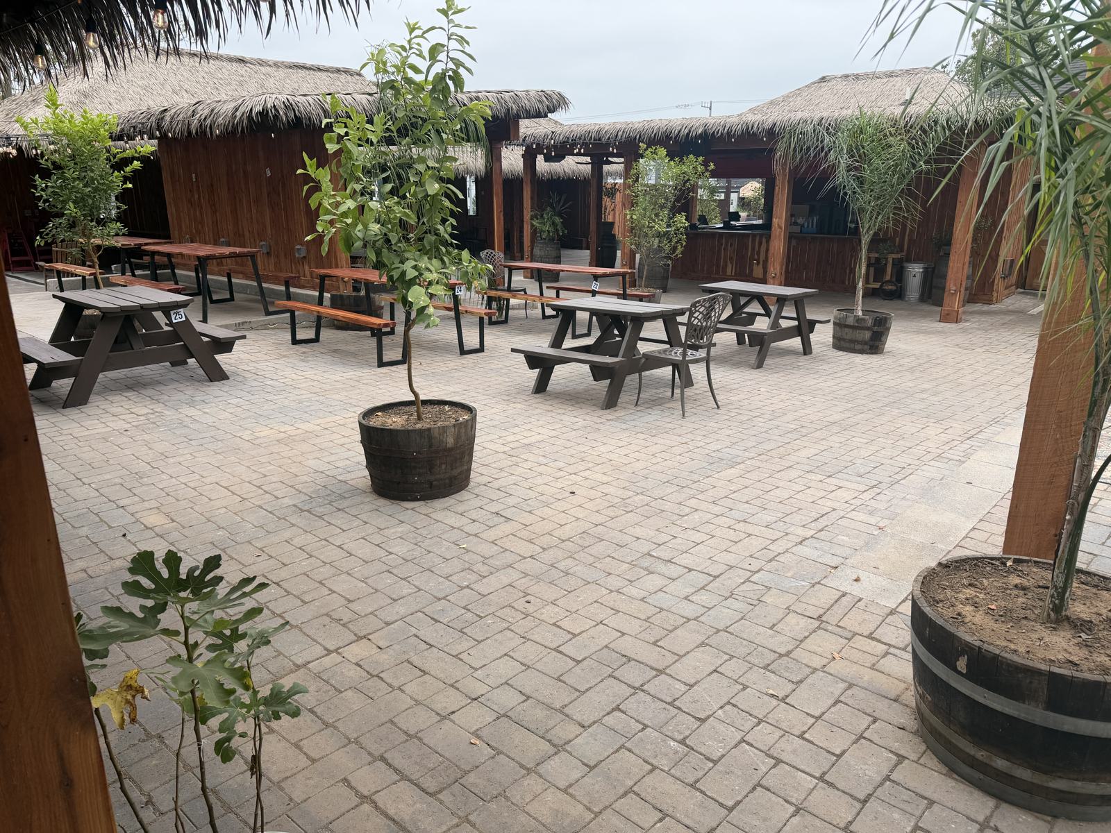 Courtyard picnic tables on permeable pavers under palm thatch roofs