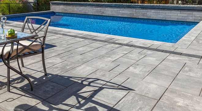 Unilock Beacon Hill Smooth pavers in Granite Fusion around a pool — manufacturer photo