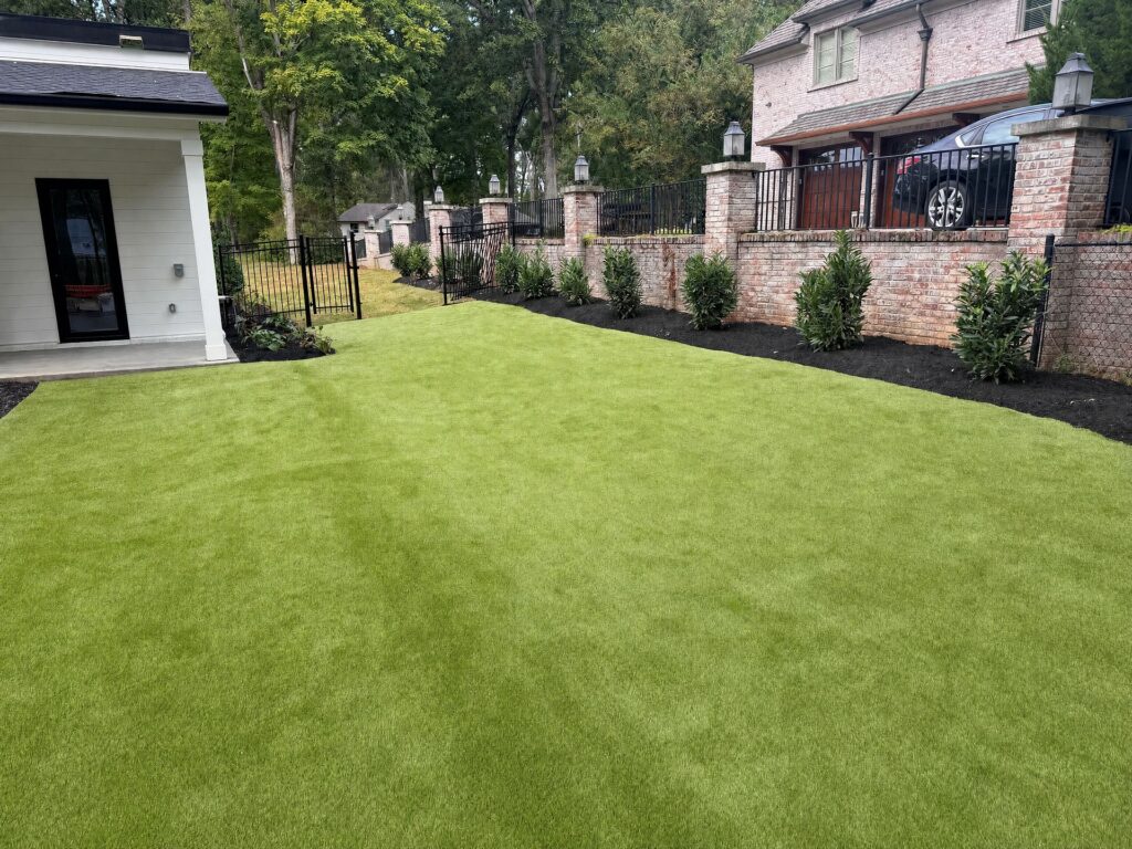 Artificial turf meeting new planting beds along a brick wall in West Meade, Nashville