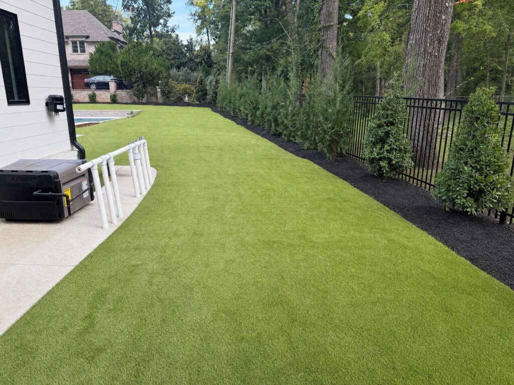 Side yard synthetic turf laid over a buried drain line where a drainage swale used to run